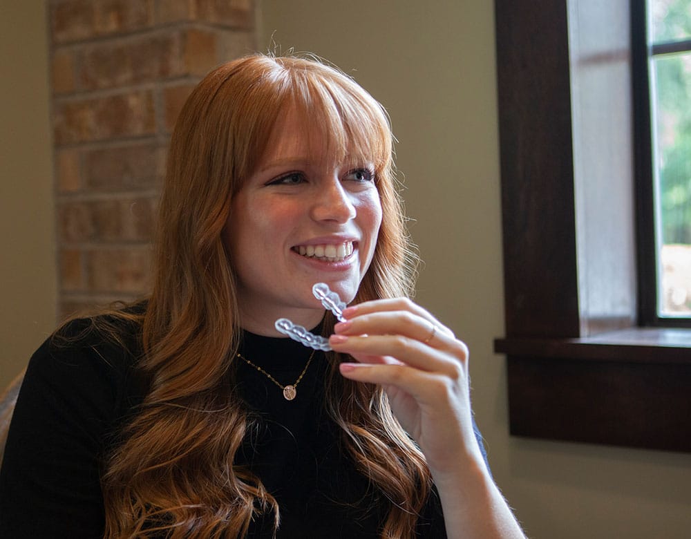 woman holding invisalign tray in her hand