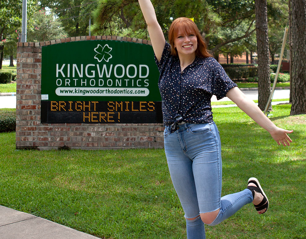 woman jumping in front of kingwood orthodontics sign